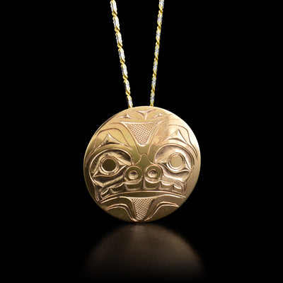 This bear pendant is round in shape and has the face of a bear facing straight ahead. The bear has teeth, a large snout, and ears.