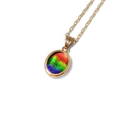 This ammolite pendant is circular in shape and has a triangular bail. The colours of the ammolite include red, orange, green, and dark blue.