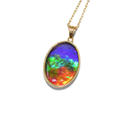 This ammolite pendant is oval in shape and has a triangular bail. The colour of the ammolite includes red, orange, yellow, green, blue, and violet.