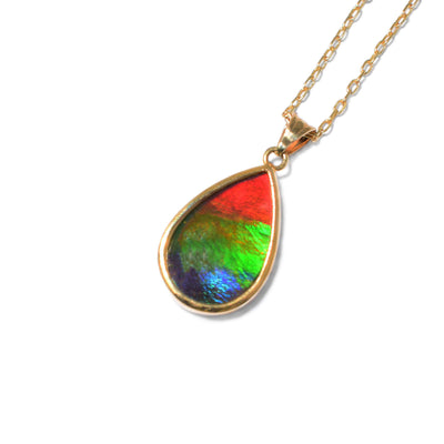 This ammolite pendant is teardrop in shape and has a triangular bail. The ammolite is a mix of red, orange, green, blue, and violet.