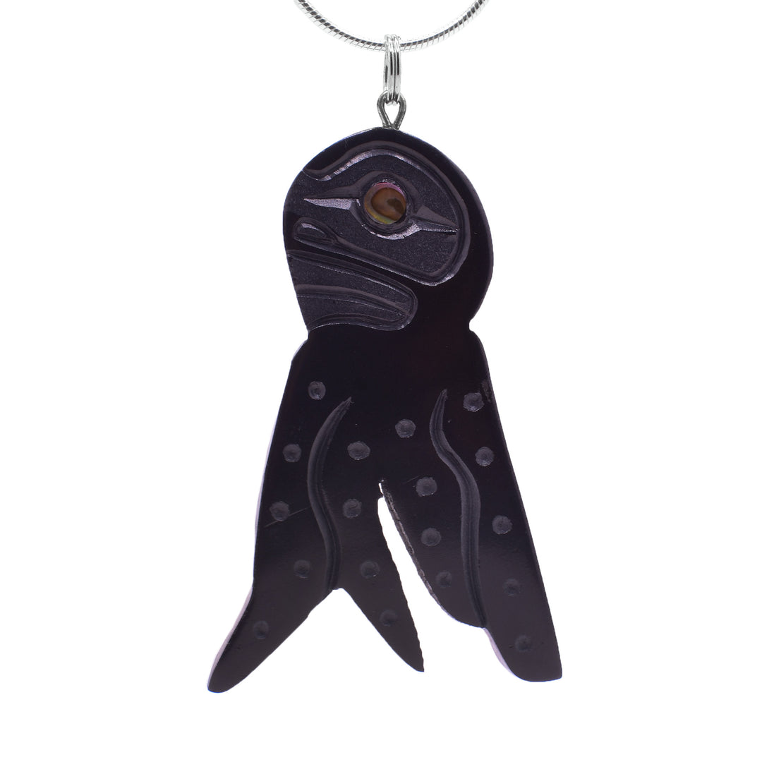 This unique octopus pendant is large and has been carved from argillite stone. The head is a circle shape and there are four tentacles carved into the piece There are carvings on the surface of the pendant detailing the head, face, suckers and tentacles of the octopus.