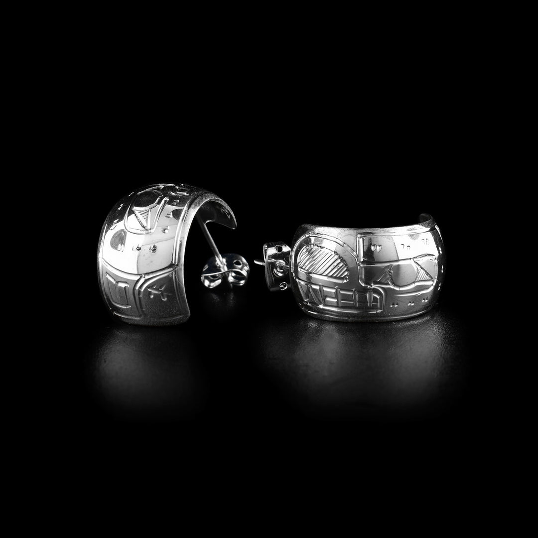 These wide hoop earrings are made from sterling silver and have a single, wide band with a gap in the back. There are carvings on the surface of the hoops depicting the Bear.
