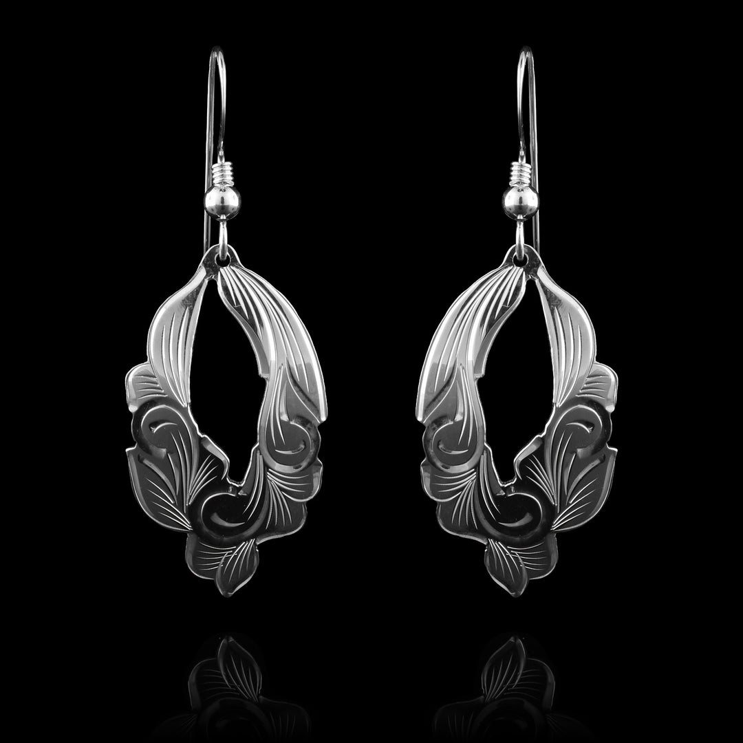 These floral dangle earrings are made from sterling silver and have roughly oval shaped hangs. There is a cutout in the center of the hangs making them appear like hoops and the edges of them follow that shapes of the floral designs. Thee are carvings on the hangs resembling leaves and petals.
