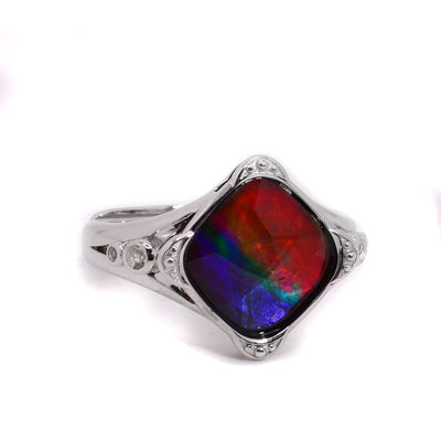 A sterling silver ring that is adjustable with a diamond shaped ammolite stone. It has topaz details along the corners of the ammolite stone and sides of the ring.