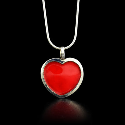 This sterling silver and enamel pendant holds the shape of a red heart. 