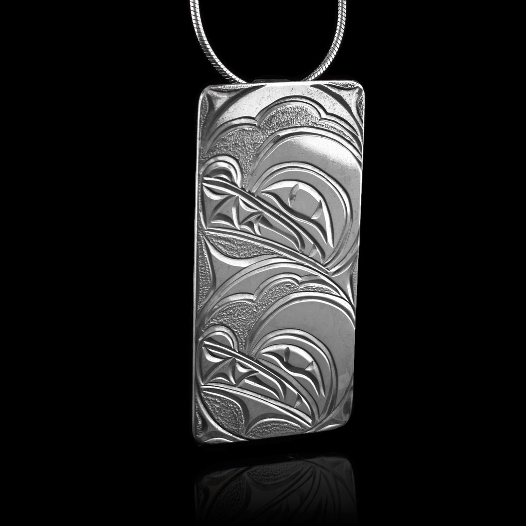This sterling silver Wolf pendant has a large rectangle shape. The head of the Wolf is depicted at a side profile in side a "womb" with a larger head representing the mother above it.