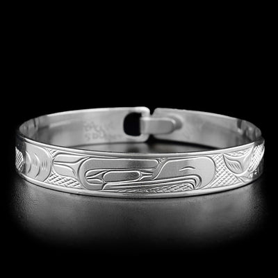 This eagle bracelet depicts the head of an eagle facing the right, chasing a salmon. Carvings behind it depict the bird's feathers.
