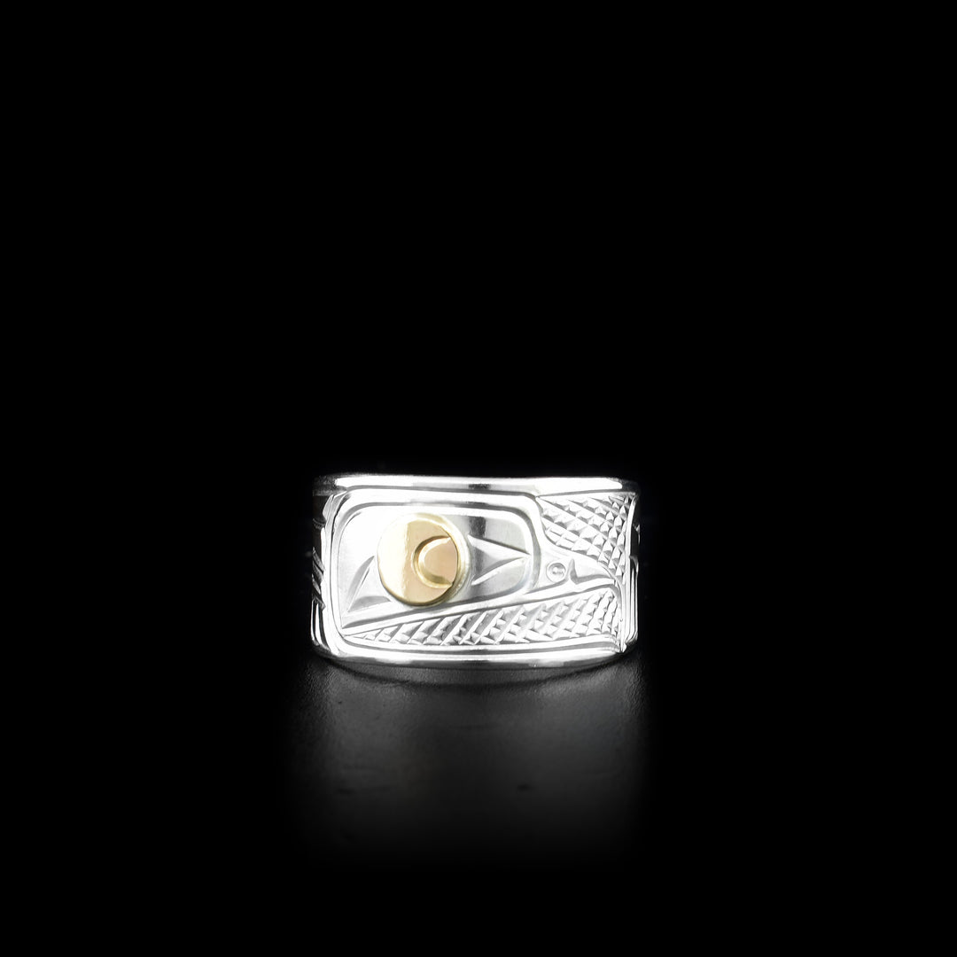 This sterling silver and 14K gold ring has a depiction of the Crow carved into the surface of it. The eye of the Crow is made from 14K gold.