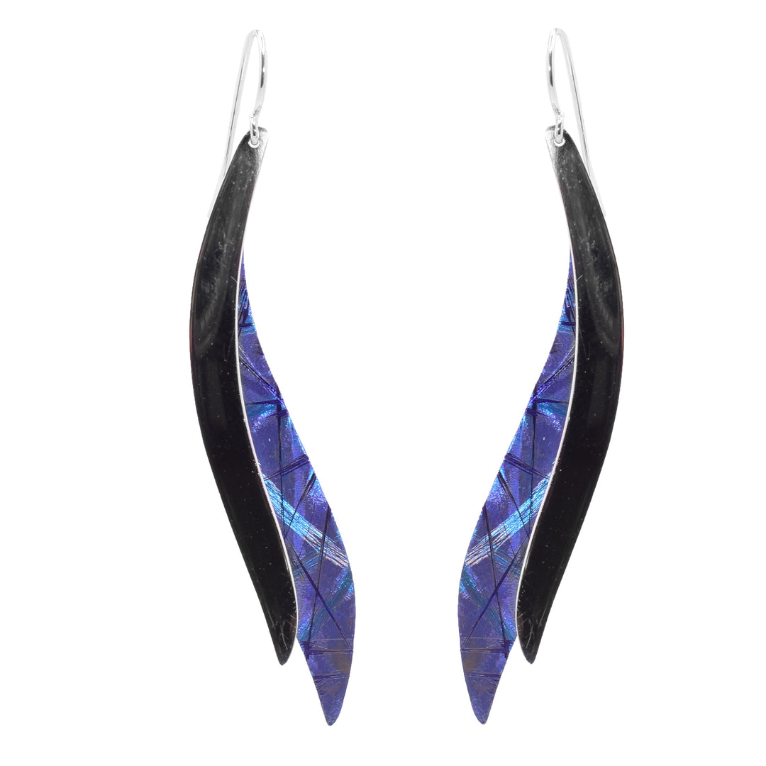 These long titanium drop earrings have two wavy bands that overlap. One is made from sterling silver and the other is titanium. There are blue and purple designs on the titanium.