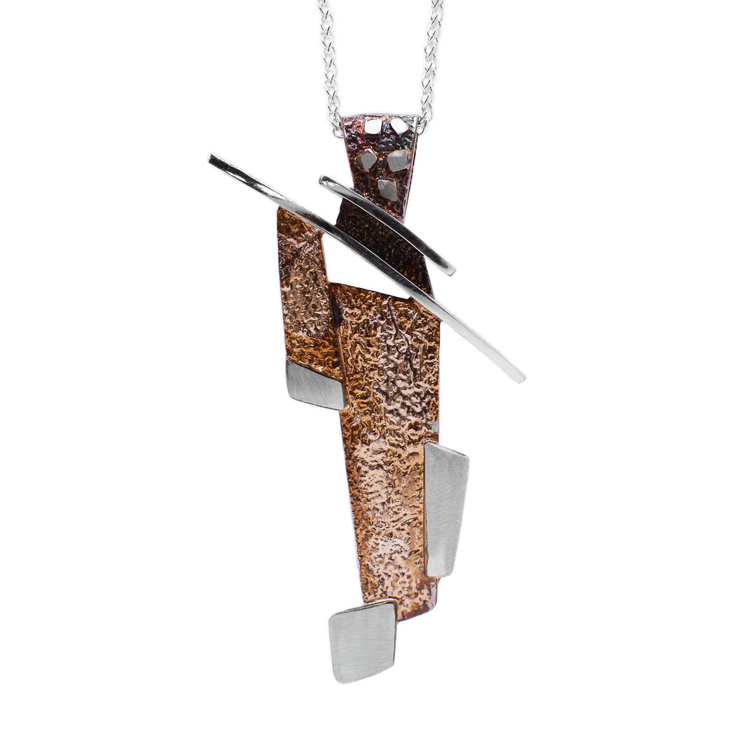This oxidized silver necklace is an abstract shape with a roof-like slanted top attached to a large, oxidized bail. The bottom of the pendant is made up of light brown rectangles and sterling silver accents stacked on top of one another.