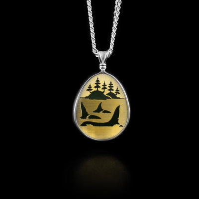 This jade pendant has a 14K gold panel with an image of three orcas and an island with trees in background cut out.