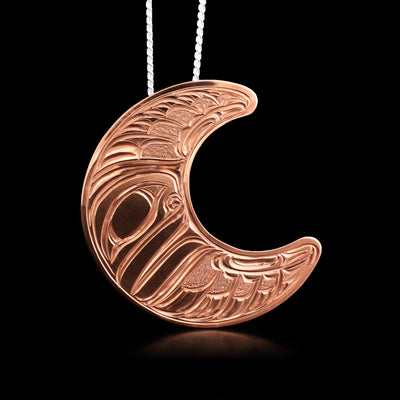 This moon pendant is in the shape of a crescent moon. The carvings depict half the face of a moon.
