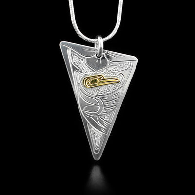 This hummingbird necklace is an assymetrical triangle shape and depicts the sideview of a hummingbird in flight facing the right of the pendant when worn. The head of the hummingbird is gold. The background is stippled.