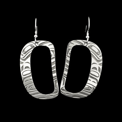 Ovoid-shaped sterling silver dangle earrings. Both earrings have an ovoid-shaped cut out and abstract designs that depict an orca.
