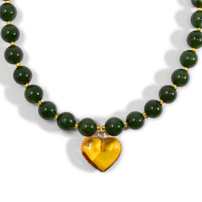 Round BC jade beads with small, light-yellow beads in between. Necklace has an amber heart pendant.