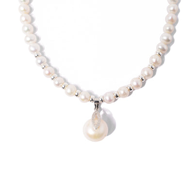 Uneven, cream-coloured pearls with silver beads between foremost pearls. Larger, pearl pendant with cubic zirconia in bail. Metal is sterling silver.