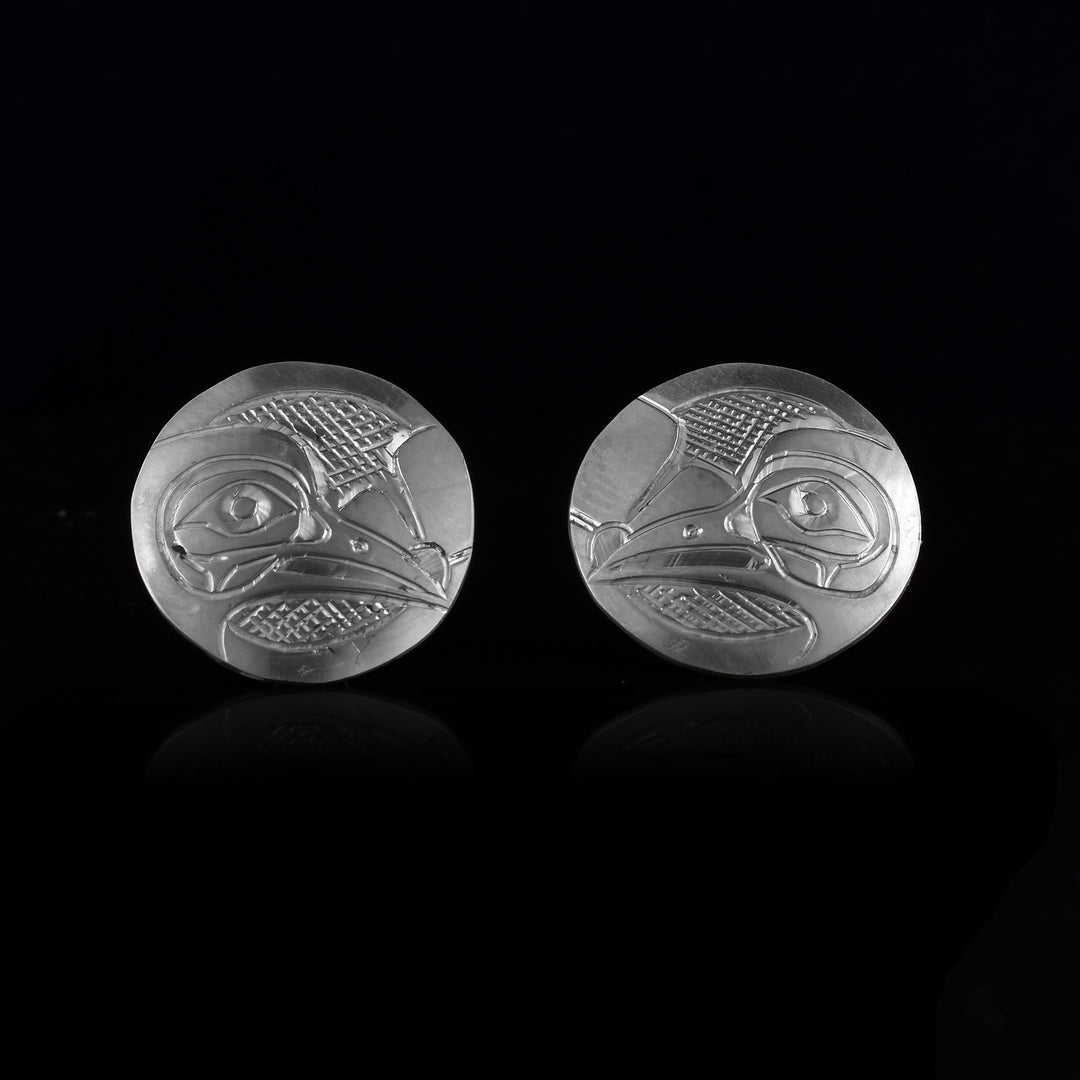 These Hummingbird stud earrings are made from sterling silver and are circle shaped. There are carvings of the side profile of the head of the Hummingbird legend made into the surface of the pieces. In the space behind the Hummingbird head, there are cross watching patterns.