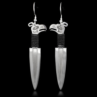 These dangle earrings are made out of sterling silver. They are shaped like a dagger, the handle of which has the shape of the Thunderbird's head.  Under the Thunderbird, the handle is wrapped in a black chord.