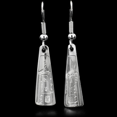 Triangle earrings carved out of sterling silver. The triangles are long, with a corner pointing up and the bottom being flat. The earrings have  a face of the Bear facing downwards engraved on the earrings.