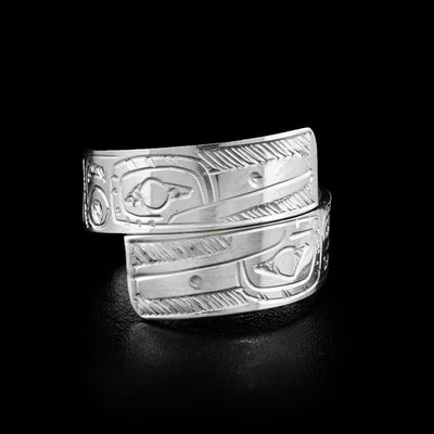 This wrap ring is made out of a sterling silver strip that has two Hummingbird faces carved on the front, where the ends of the ring overlap. The face of the lower Hummingbird is upside down.