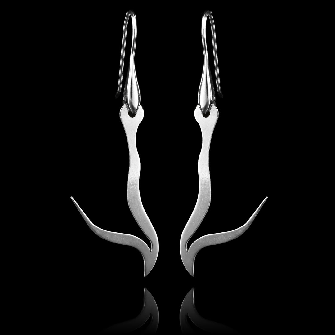 These sterling silver long dangling earrings have thin hangs that drop down and have points protruding from them. The hangs depict a Haida Gwaii character.