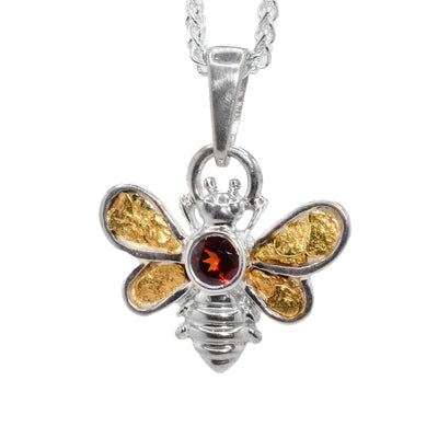 Sterling silver bee pendant with 22K gold nuggets in wings. Round, faceted garnet set on back. Sterling silver bail. By Tom Gregorczyk.