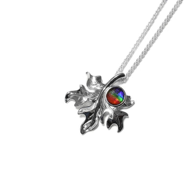 Sterling silver wavy maple leaf pointing downwards. Round piece of ammolite set on left side next to stem. Chain goes through stem.