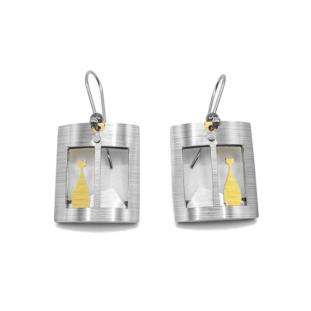 Each earring is a curved, rectangular brushed and anodized aluminum silver-colour window. Gold-colour cat and silver-colour hill in window. Stainless steel hooks. By JR Franco.