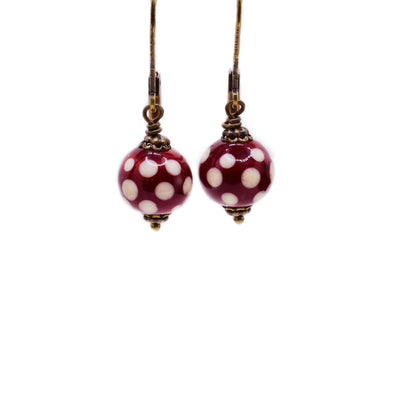 Brass lever-back earrings with round, handmade lampworked glass beads. Beads are red with white polka dots. By Wendy Pierson.