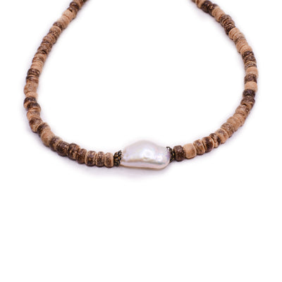 Anklet with cylindrical coconut wood beads and a white baroque pearl in the center with brass adornments on either side.