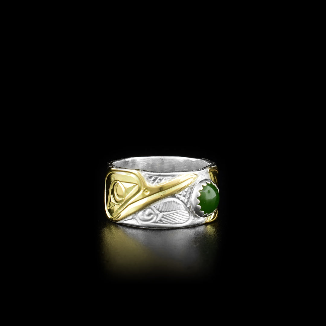 This Hummingbird ring is made from sterling silver, 14K gold and BC jade with a sing with band. There is a round, jade gem held in the center of the band and there are designs carved into the surface of the band. The carvings depict the Hummingbird and its head is made from 14K gold.