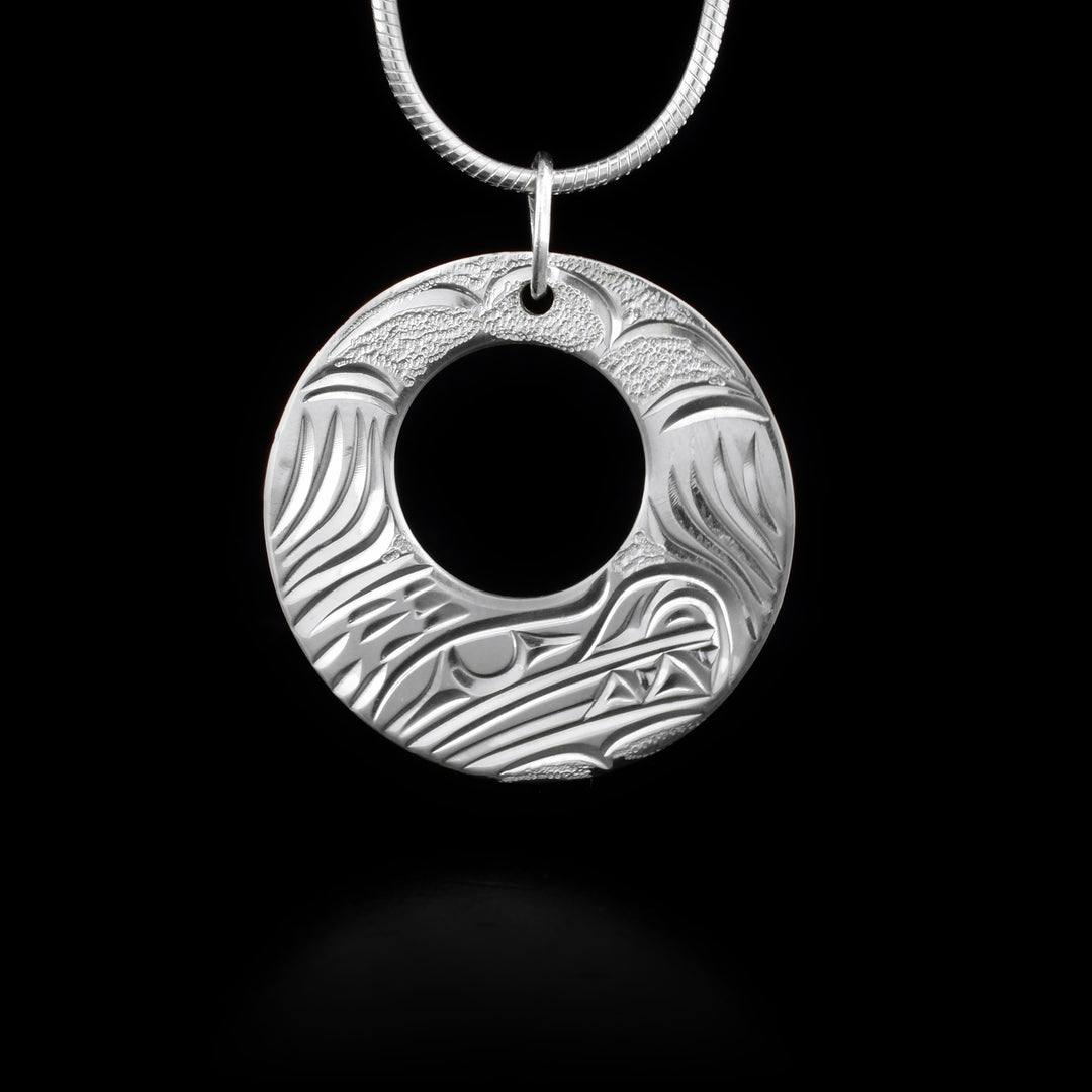This bear pendant has cut out circle and features a bear. Jump ring for bail. Hand-carved by Kwakwaka’wakw artist Cristiano Bruno.