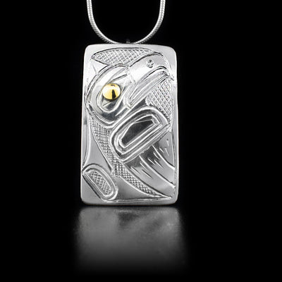 Sterling silver rectangular pendant featuring eagle with 14K yellow gold in eye. Cross-hatching background. By Heiltsuk artist Reg Gladstone.