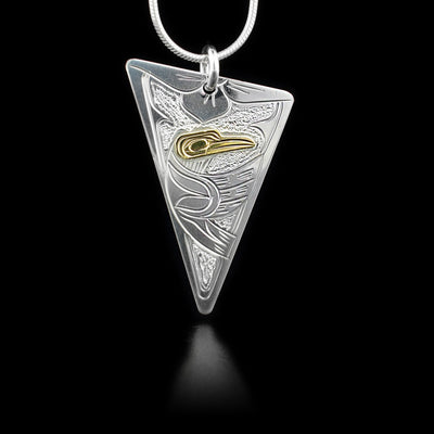 Sterling silver downwards-pointing triangle pendant featuring hummingbird flying below flower. Hummingbird has 14K yellow gold head. Textured background.