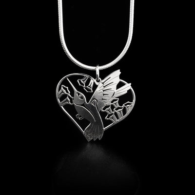 This hummingbird pendant depicts a hummingbird mid-flight surrounded by flowers in a heart-shaped frame. Background has been cut out.