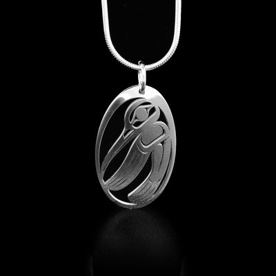 This hummingbird pendant depicts the side-view of hummingbird facing right, head down and wing outstretched in oval frame. The background has been cut out.