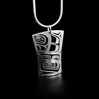 This raven pendant is an abstract box shape with pieces of it cut out in the center to represent a raven and its feathers.