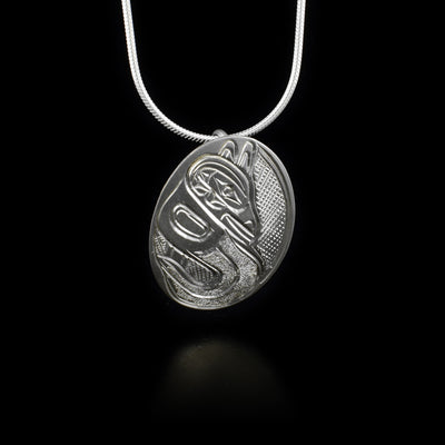 Oval sterling silver pendant depicting raven standing in water.