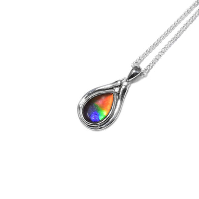 Teardrop AA-grade ammolite set in sterling silver. White topaz set above ammolite. Sterling silver outline in a pear shape surrounds ammolite and white topaz.