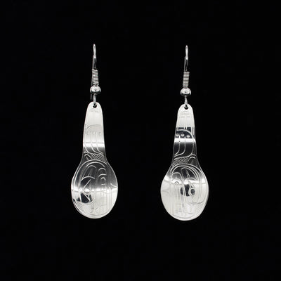 Dangle earrings hand-carved by Coast Salish artist Travis Henry. Each earring depicts the side-view of a bear’s head and paw on the spoon. Each earring measures 2” x 0.6” including hook.