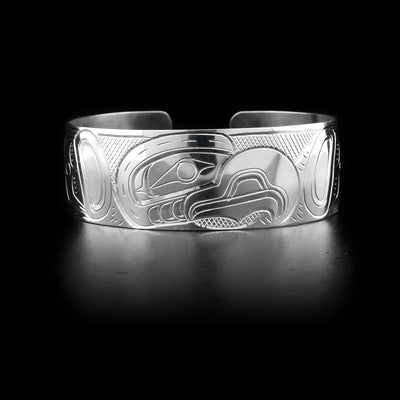 Bracelet features eagle head facing left on front with cross-hatching background. Hand-carved by Kwakwaka’wakw artist William Cook.