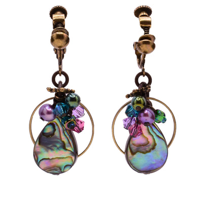 Dangle clip earrings made of Swarovski crystal, handworked brass, pressed glass, freshwater pearls, and abalone. Brass ear clips. By Honica.