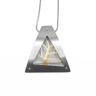 Large, triangular frame in silver, gold tree inside. Hidden bail on back. Pendant is brushed and anodized aluminum. Minimalist design.