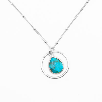Pendant necklace with flat, faceted turquoise teardrop dangling in hoop. Satellite chain included. All metal is sterling silver.