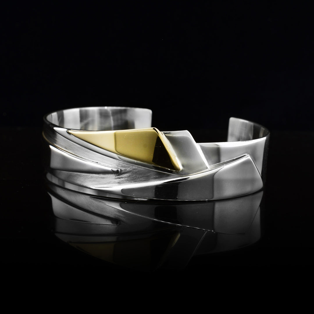 This Two Tone Triangle Cuff is made with sterling silver with a pattern of triangle sails and one 14k gold triangle to draw the eye in.