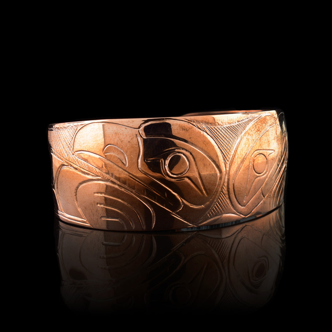 This copper bracelet cuff has carvings that depict the RAVEN. The two heads of the raven are facing away from one another and they are looking out.