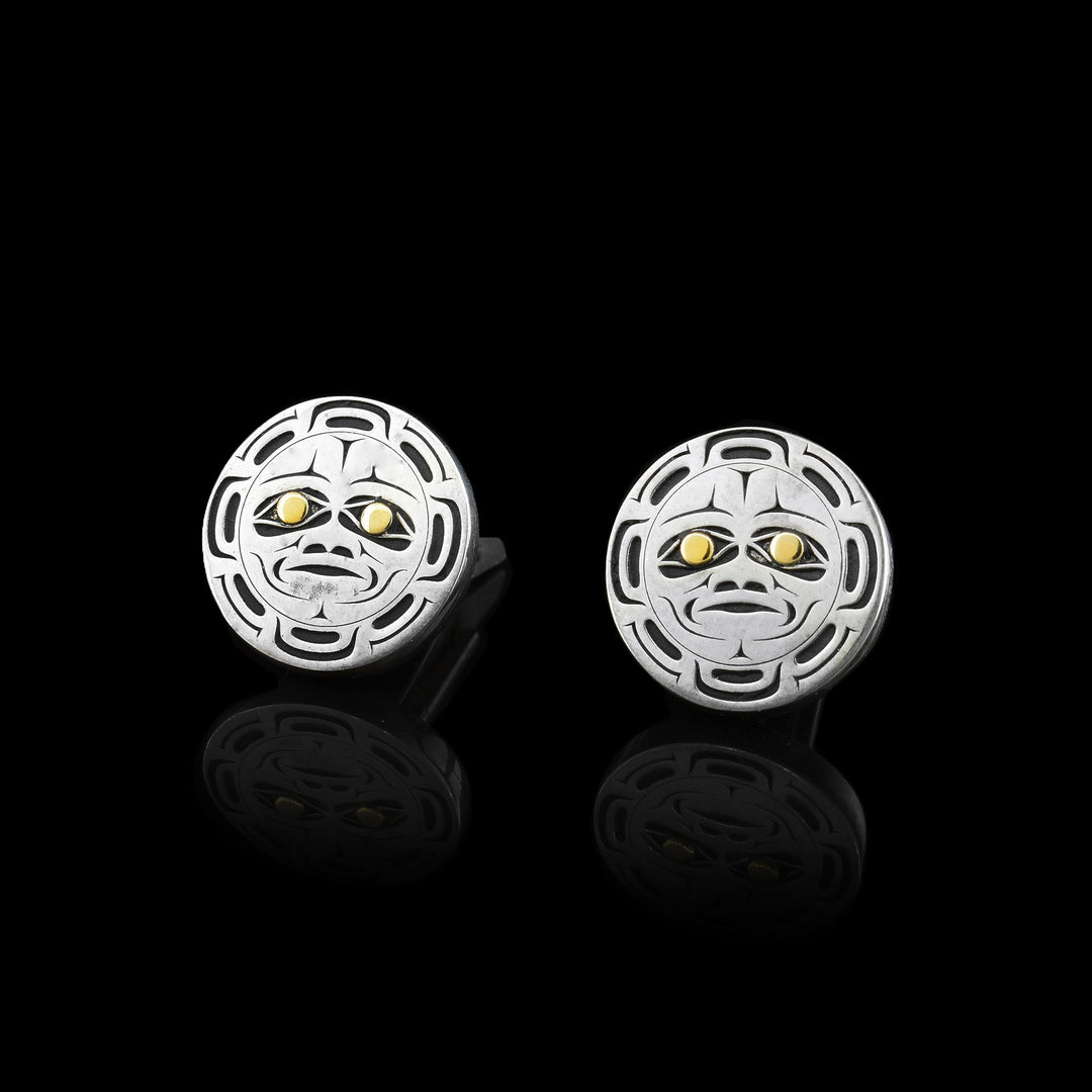 These gold and silver Moon cufflinks are circular in shape and is made from sterling silver and 14k gold. There are cutout designs depicting the face of the moon in the center with its eyes, eyebrows, nose and mouth detailed. Surrounding the face, there are "moon ray" designs. The eyes of the legend are made from 14k gold.