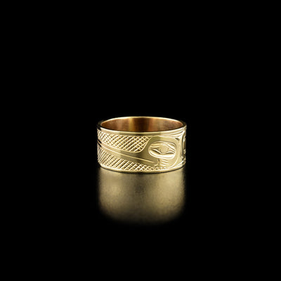 14k Gold 3/8" Hummingbird Ring by Harold Alfred. In the center of the ring there is the profile of a hummingbird's head facing towards the left with a long, narrow beak. To the right of the hummingbird's head is the continuation of it's body including the neck, the wings, and the tail. The hummingbird has a feather on its head. To the left of the hummingbird's head there are intricate designs representing flowers of which the hummingbird is drinking from.