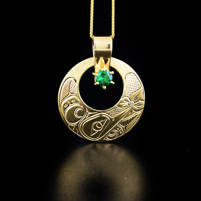 Cut-out hummingbird pendant hand-carved by Coast Salish and Cree artist Richard Lang. Made of 14K gold and a lab-created emerald. Pendant measures 1.50" x 1.25" including bail. Chain is not included.