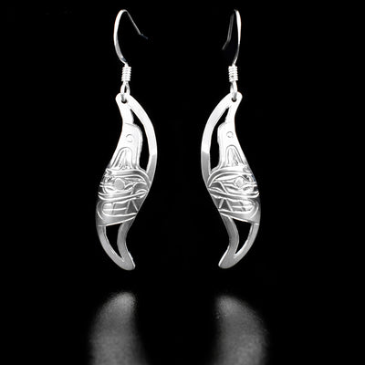 Sterling Silver Leaf Style Orca Earrings by Harold Alfred. Each earring is in the shape of a leaf. On the inside of each earring the artist has hand-carved the profile of a killer whale's (orca's) head facing inward. The orca has a long fin above its head and open, sharp teeth. The background has been cut out.
